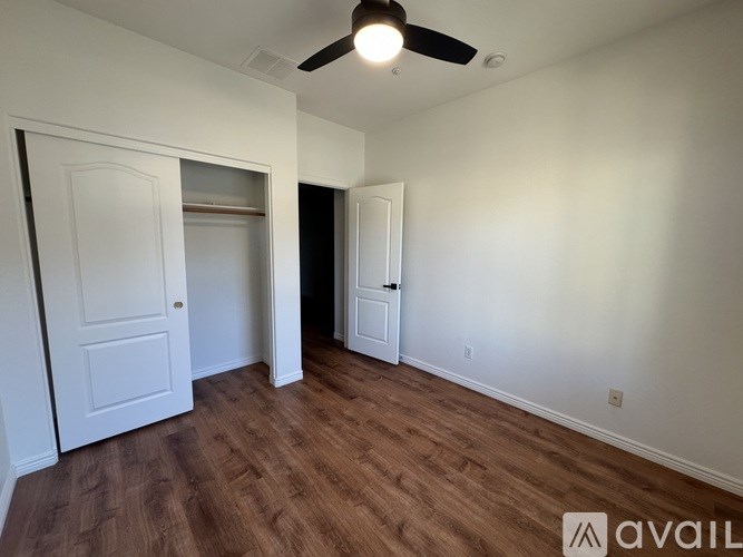A room with a ceiling fan and wooden flooring.