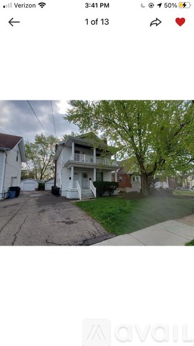A white two-story house with a tree in front.