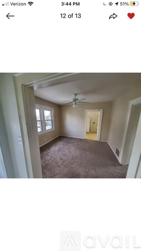 A room with a carpeted floor and a ceiling fan.