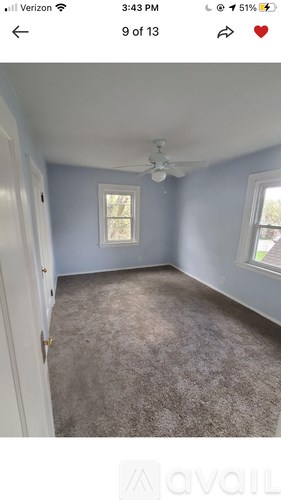 A room with a carpeted floor and a ceiling fan.