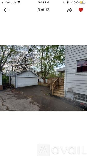 A white house with a garage and a wooden staircase leading to the door.
