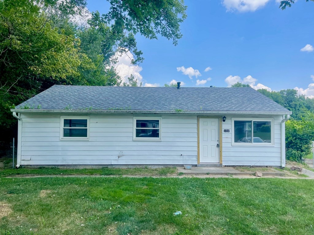 A small white house with a grey roof and a brown door.