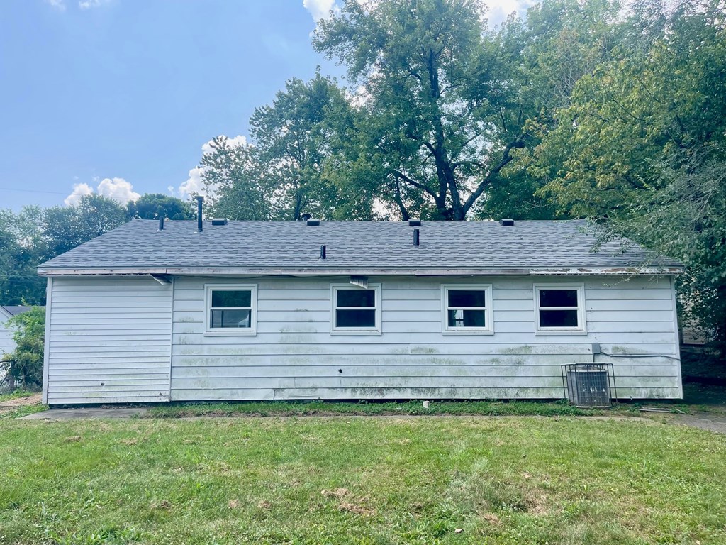 A white house with a grey roof and three windows.