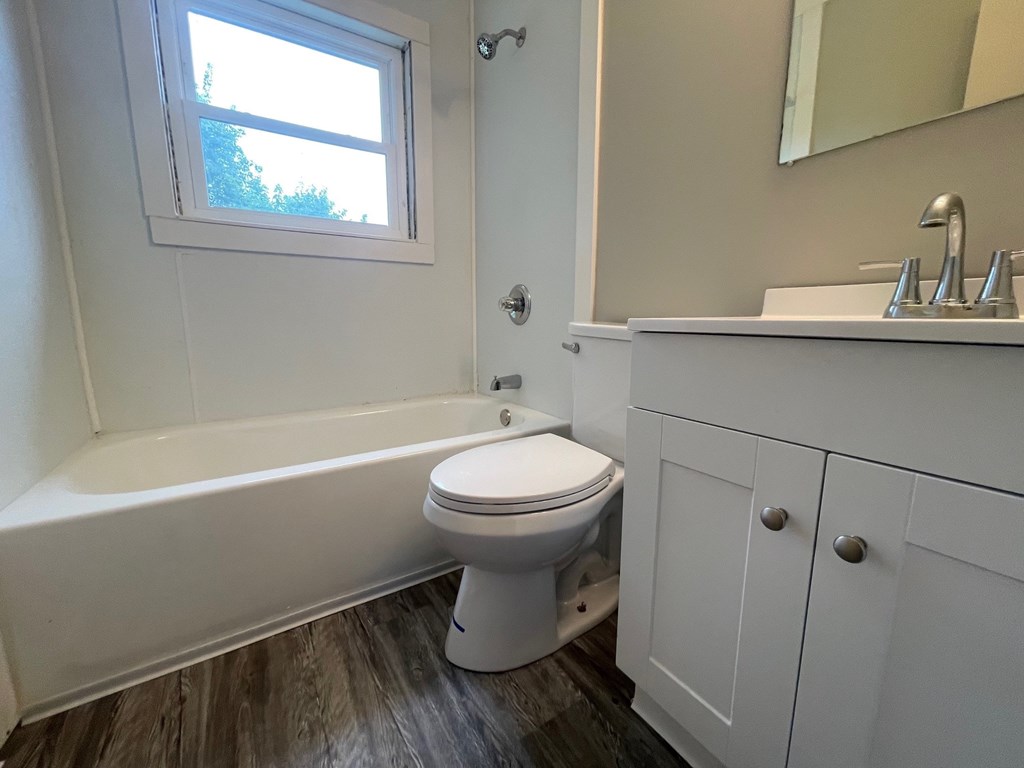 A white toilet sits in a bathroom next to a bathtub.