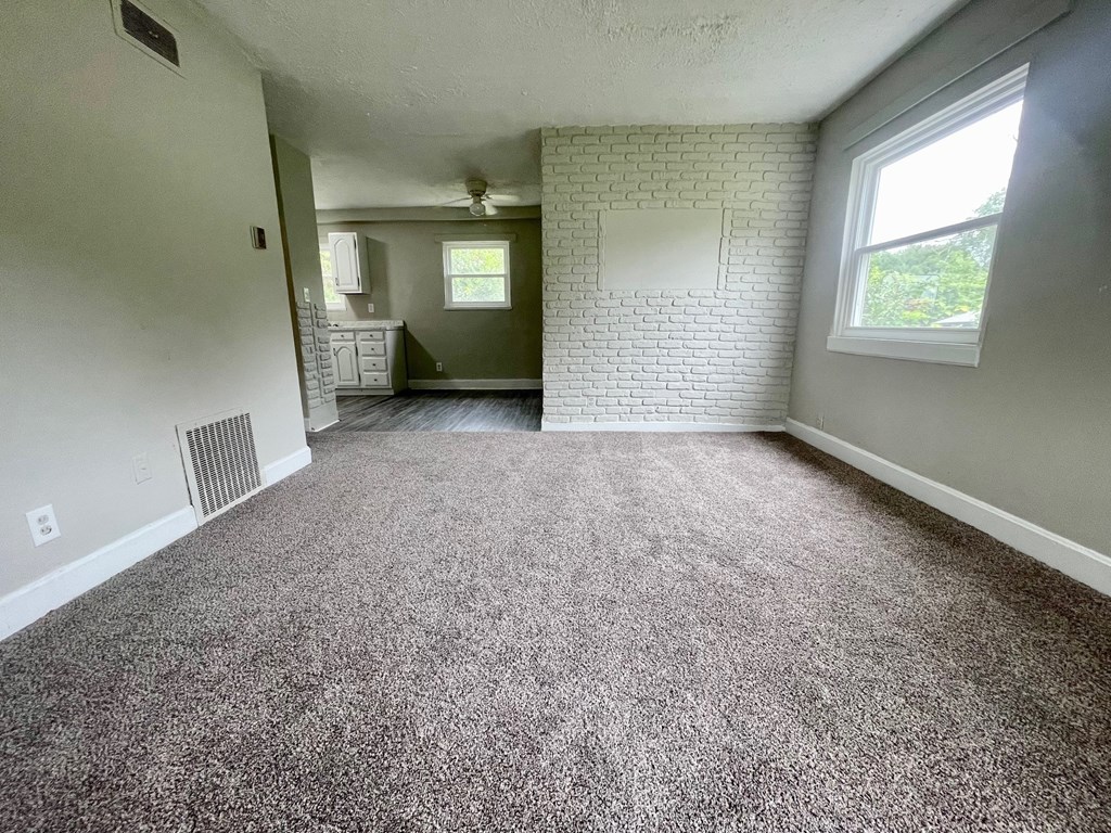 A room with a carpeted floor and a white brick wall.