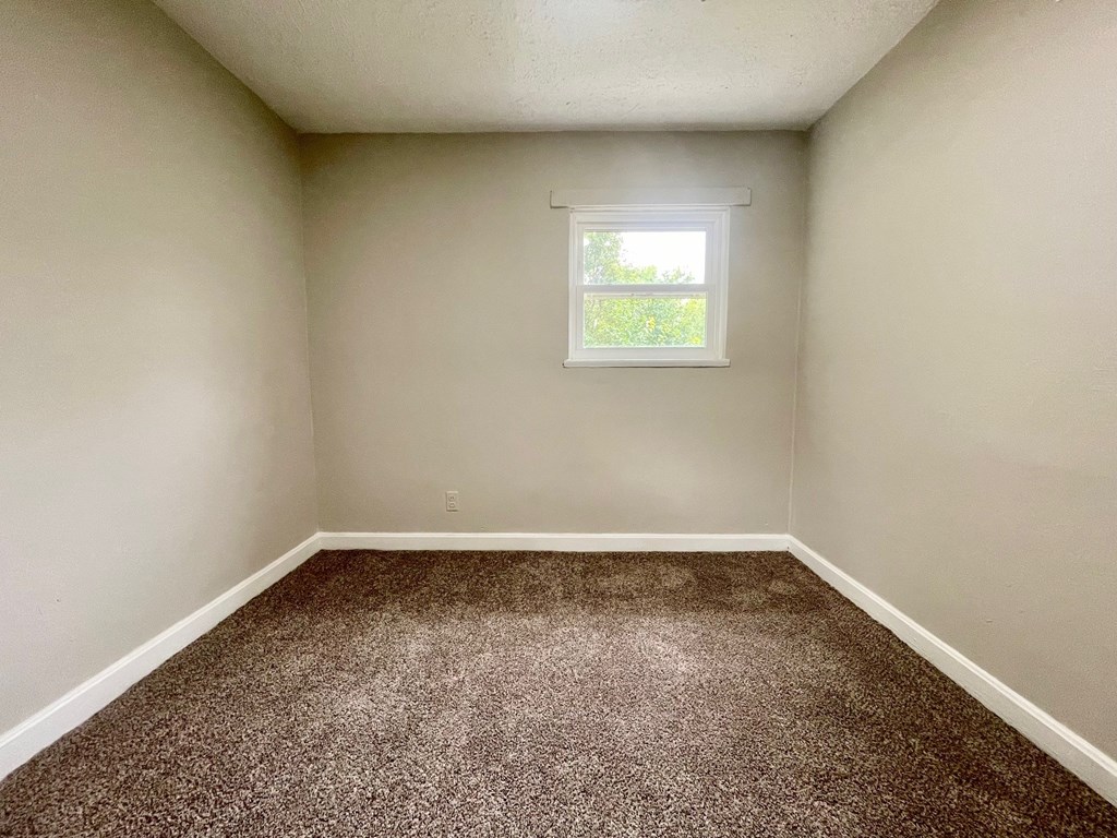 A room with a carpeted floor and a window.