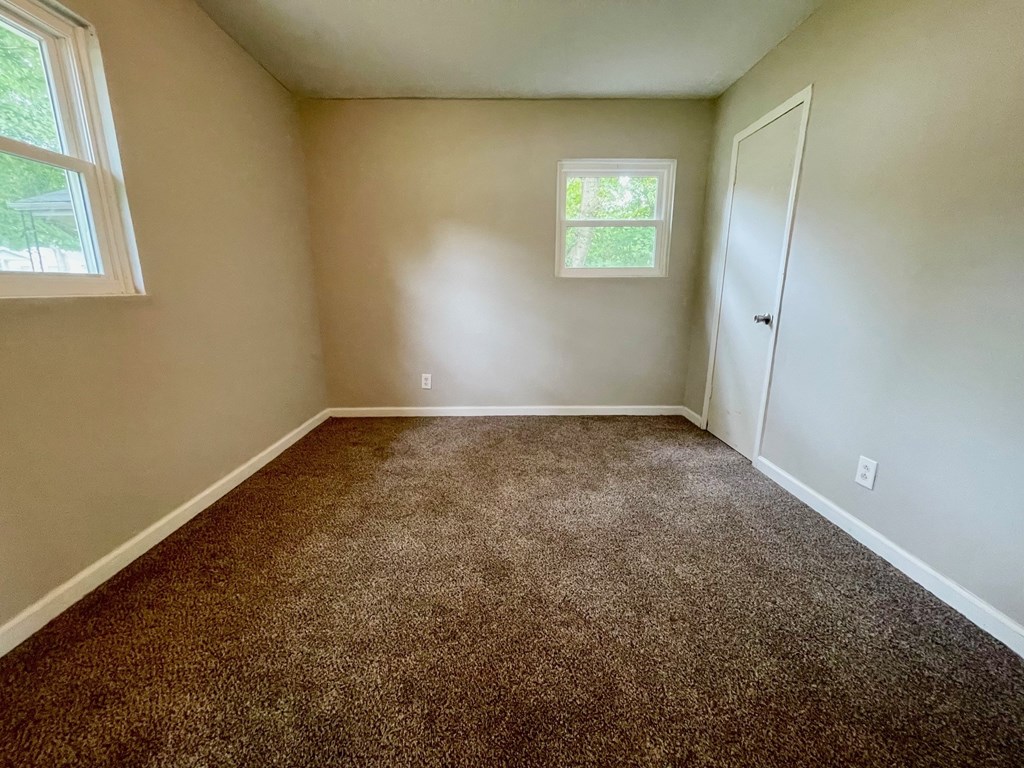 A room with a carpeted floor and a window.