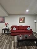 A red couch with a white pillow is in the middle of a room.