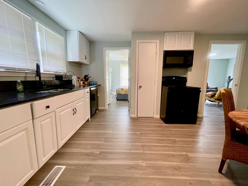A kitchen with white cabinets and a black counter top.