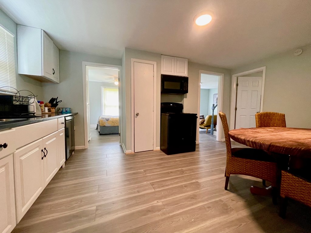 A kitchen with white cabinets and a black fridge.