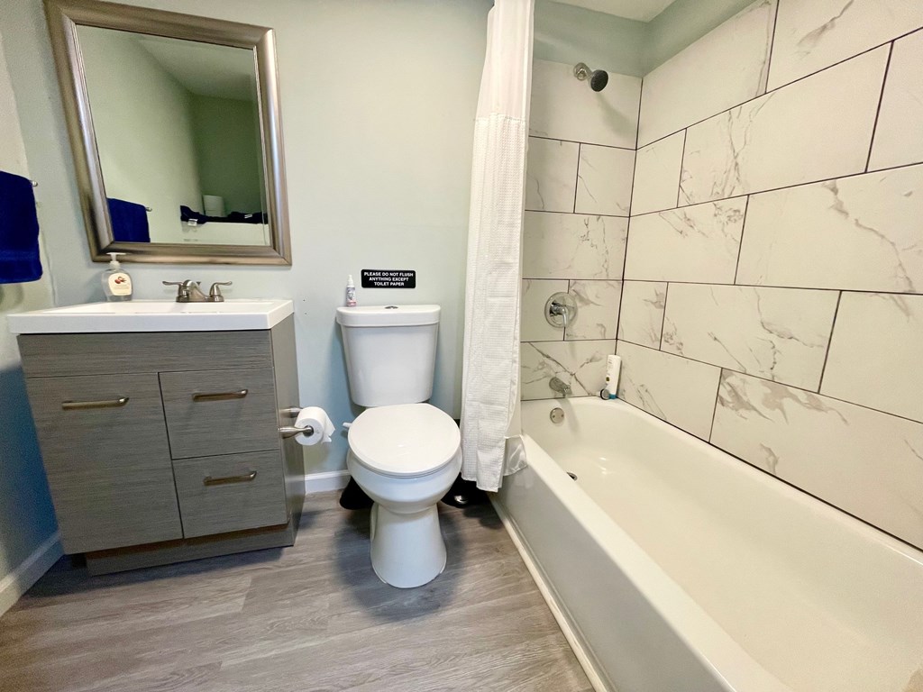 A white toilet is in a bathroom with a marble wall.
