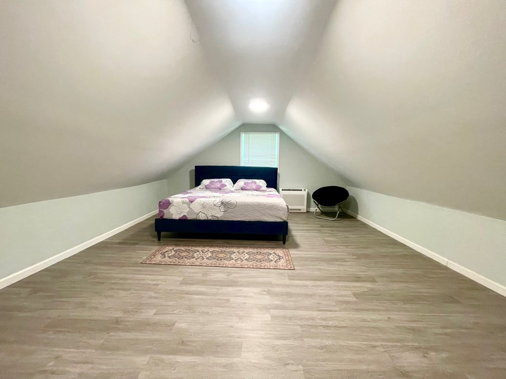 A bedroom with a bed and a chair.