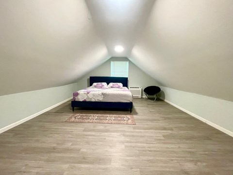 A bedroom with a bed and a chair.