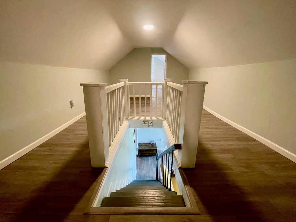 A staircase with a black railing and wooden steps leading to a doorway.