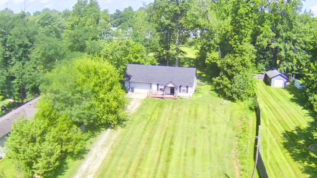 A house is surrounded by a lush green lawn and trees.