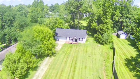 A house is surrounded by a lush green lawn and trees.