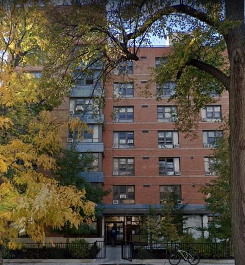 A tall apartment building with a bicycle parked in front.