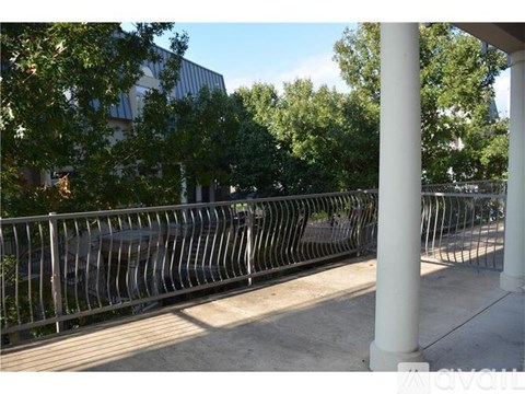 A metal fence is in front of a building with trees in the background.