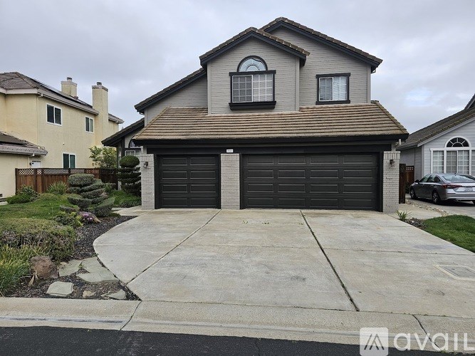 A house with a grey roof and two black garage doors.