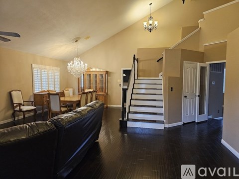 A living room with a black couch and a chandelier.