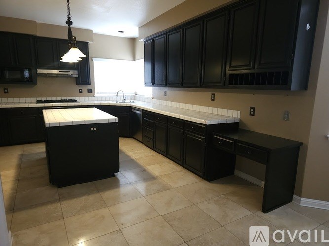A kitchen with black cabinets and a white island.