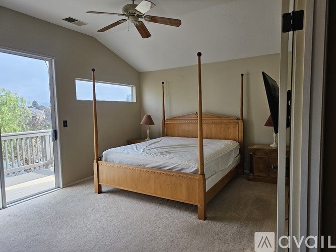 A bedroom with a bed, a ceiling fan, and a sliding glass door.