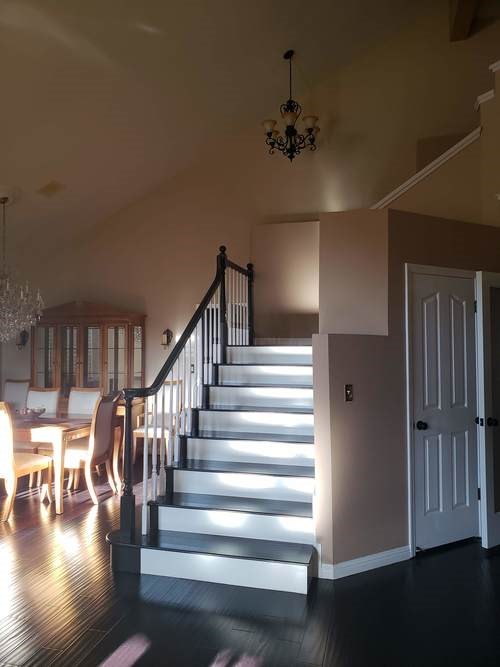 A staircase with a chandelier and a dining table in the background.