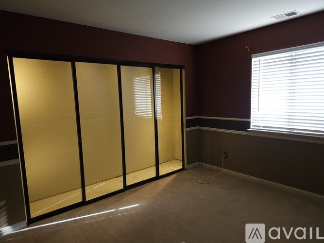 A room with a large glass door and a window with blinds.