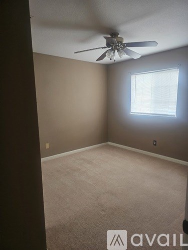 A room with a ceiling fan and a window with blinds.