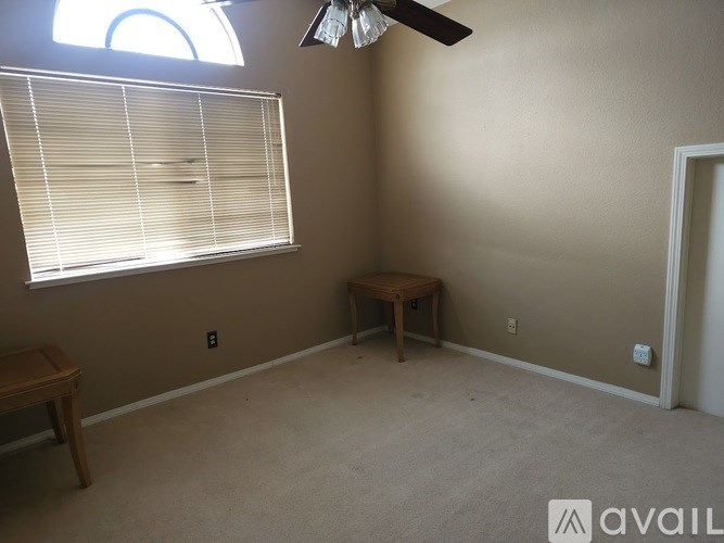 A room with a window, a fan, and a table.