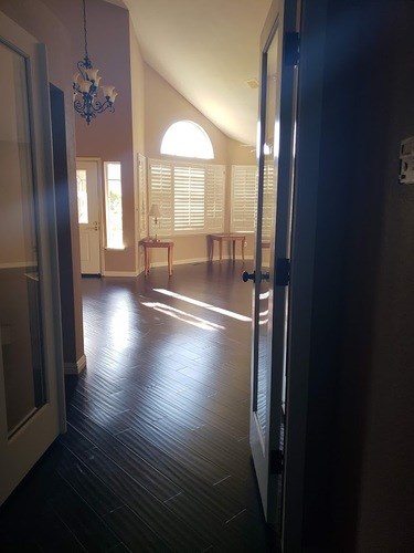 A hallway with a chandelier and a table with chairs.