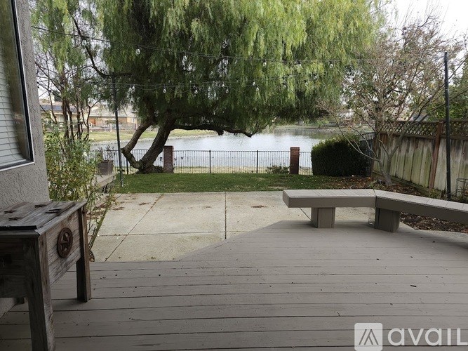 A wooden bench sits on a deck overlooking a lake.