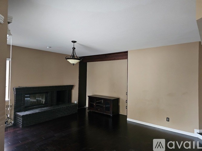 A living room with a fireplace and a hanging light fixture.