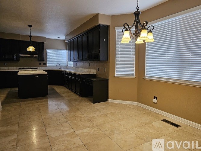 A kitchen with black cabinets and a tiled floor.