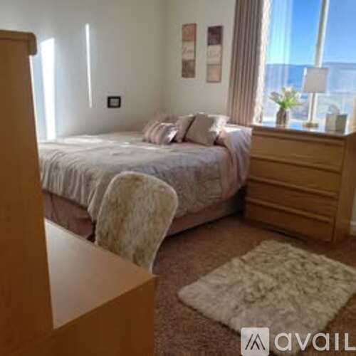 A bedroom with a large bed and a window overlooking the city.