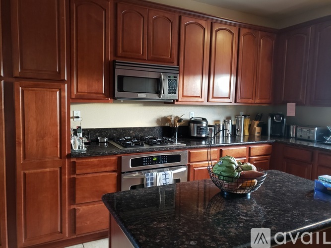 A kitchen with brown cabinets and black countertops.