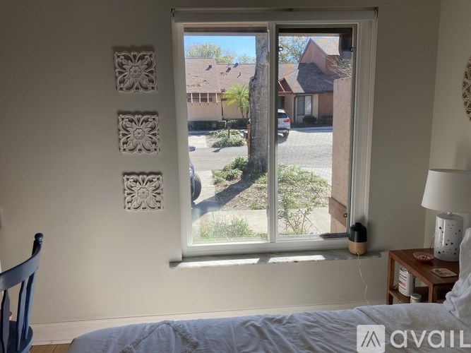 A bedroom with a large window overlooking a street.