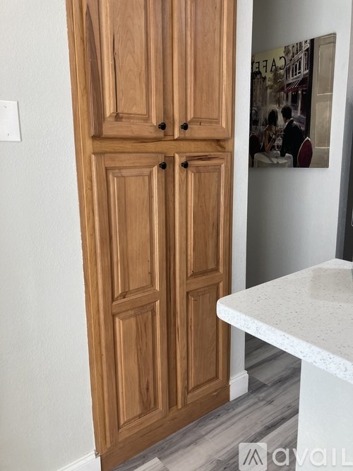 A tall wooden cabinet with two doors stands next to a white counter.