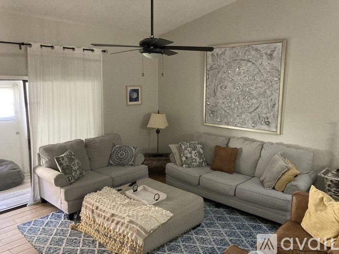 A living room with two couches, a rug, and a ceiling fan.