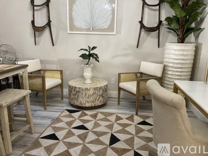 A living room with a brown and white rug, a wooden table, a white vase, and a plant.