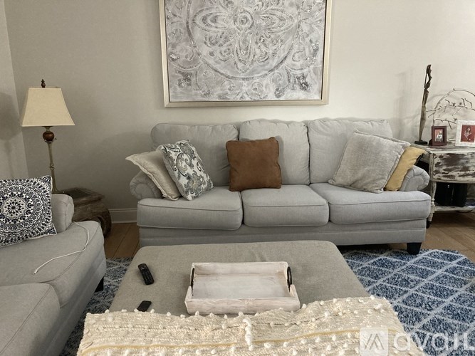 A grey couch with a white throw pillow sits in a living room.