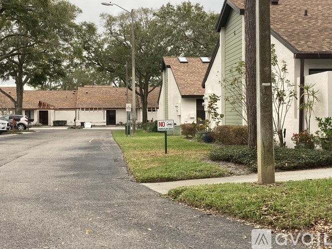 A sign in front of a house with a green lawn.