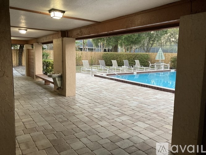 A patio with a pool and chairs.