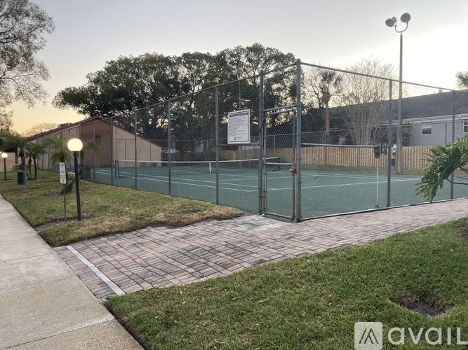 Tennis court surrounded by a fence and a signboard.