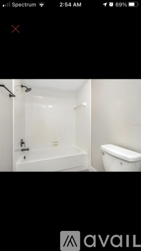 A white bathtub is in a bathroom with a toilet.
