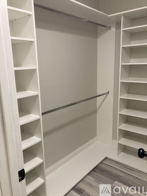 A white closet with shelves and a black handle.