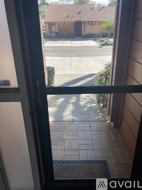 A view from inside a building looking out to a driveway and a house.