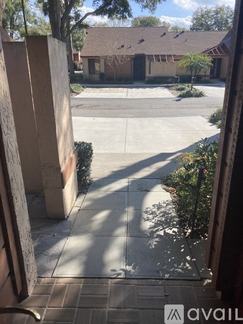 A view from a doorway looking out to a driveway and a house.