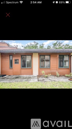 A brown house with a black roof and a small front yard.