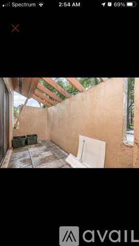 A patio with a white chair and a brown wall.